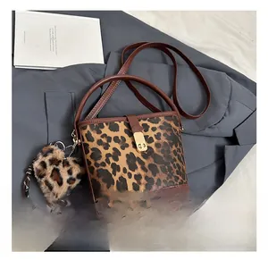 Detail shot of leopard print bucket bag featuring gold buckle and plush heart charm
