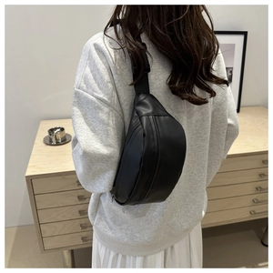 Minimalist black leather chest bag with adjustable strap worn on back, Nordic style