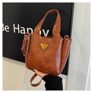 Close-up of brown textured leather handbag with gold triangular logo and dual handles