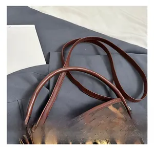 Detail of leopard print bucket bag with gold metal buckle and brown leather strap