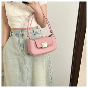 Gros plan d'un sac baguette rose avec boucle dorée et détails de nœuds sur la bandoulière