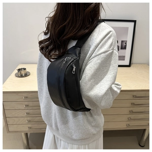Close-up of minimalist black matte crossbody bag featuring dual zippers and adjustable strap