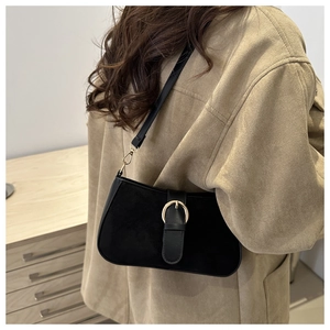 Detailed view of a vintage black suede baguette bag with a prominent gold ring buckle