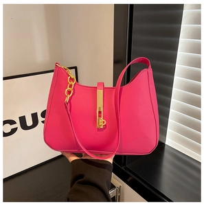 Detail einer magentafarbenen PU-Handtasche mit goldener Schnalle und Kettengliedern