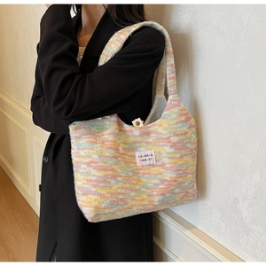 Dettaglio di borsa tote in maglia a righe arcobaleno con trama morbida e tracolla