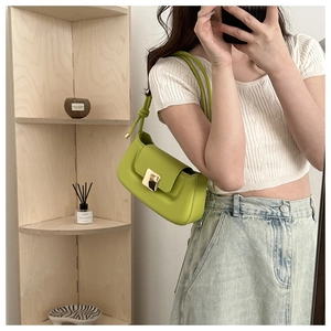 Détail du sac baguette en cuir vert avec boucle dorée et décoration de poignée à nœud