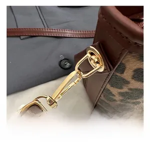 Close-up of leopard print bucket bag with gold metal hook and brown leather trim