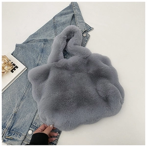Détail d'un sac à main gris en peluche posé sur une veste en jean tendance