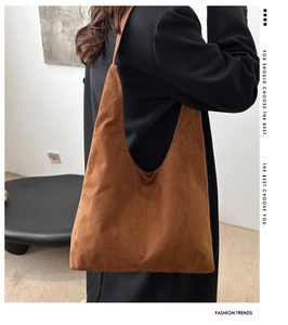 Detailed texture of brown matte suede shoulder bag shown on a model in a black suit