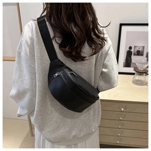 Close-up of minimalist black crossbody chest bag with dual silver metal zippers on model