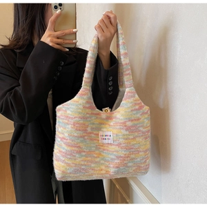 Dettaglio ravvicinato di una borsa tote in maglia soffice colorata con etichetta tessuta