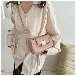 Mannequin portant un sac baguette beige chic avec boucle dorée et fine bandoulière en cuir