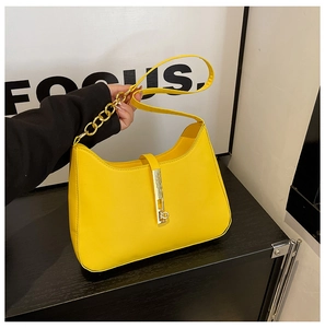 Detail der gelben PU-Handtasche mit goldener Kette und rechteckigem Metallverschluss