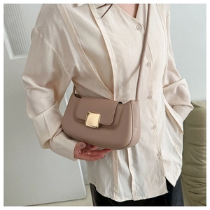 Gros plan du sac baguette en cuir kaki avec boucle dorée porté dans un intérieur chic