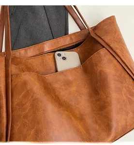 Detail view of large brown tote bag featuring a practical front pocket for smartphones