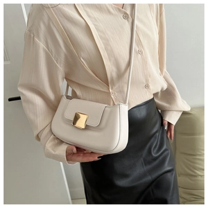 Détail d'un sac baguette en cuir crème avec boucle dorée porté par un mannequin
