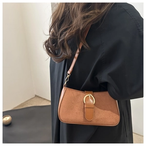 Detailed close-up of brown suede underarm bag with gold metal ring and strap