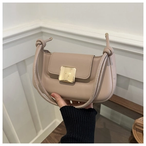 Gros plan du sac baguette en cuir rose avec boucle dorée et détail de bandoulière nouée