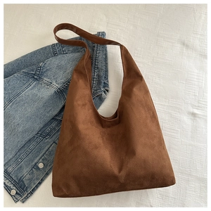 Detail of dark brown matte suede hobo bag with leather strap on denim jacket