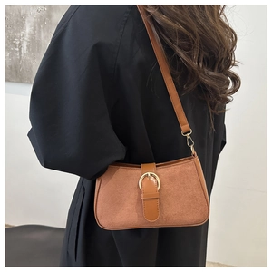 Detail of vintage brown suede crossbody bag with gold circular metal buckle