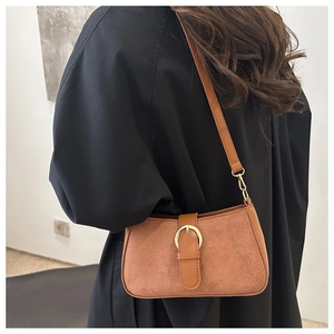 Close-up of vintage brown suede shoulder bag with gold buckle and adjustable leather strap
