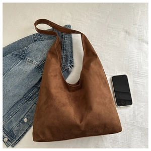 Flat lay of brown frosted suede tote bag next to a blue denim jacket and phone