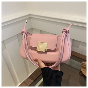 Détail du sac baguette en cuir rose avec boucle dorée et bandoulière à nœuds élégante
