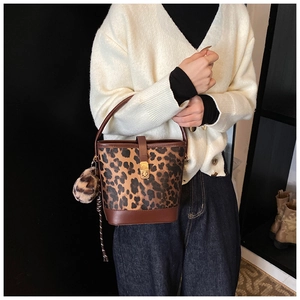 Detailaufnahme der Leoparden-Beuteltasche mit Goldverschluss und Plüschball-Anhänger