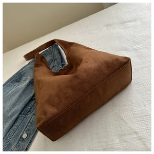 Detailed view of brown suede hobo bag with neat stitching on white textured cloth