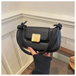 Détail du sac baguette noir avec boucle carrée dorée et bandoulière à nœuds élégante