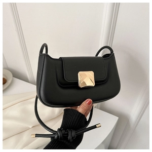 Gros plan d'un sac baguette noir avec boucle carrée en métal doré et bandoulière à nœuds