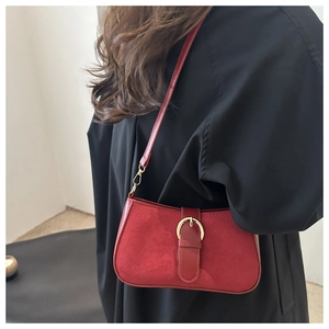 Detail of red vintage baguette bag with matte suede texture and gold horseshoe buckle