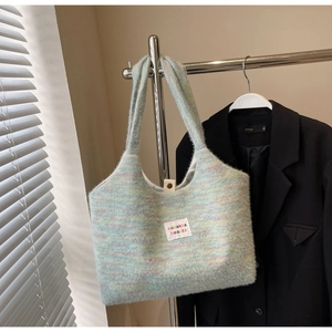 Dettaglio di borsa tote in maglia colorata con etichetta bianca e chiusura a bottone