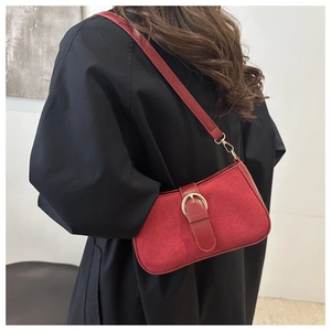 Detail of red frosted suede shoulder bag with gold metal buckle on black coat