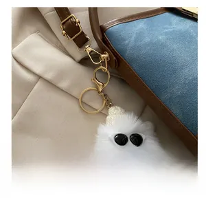 Close-up of fluffy white plush charm with glasses on a bucket bag with gold clasp