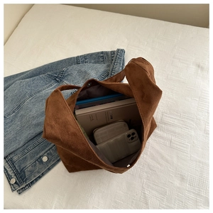 Detail of large brown corduroy tote bag showing spacious interior with books and phone
