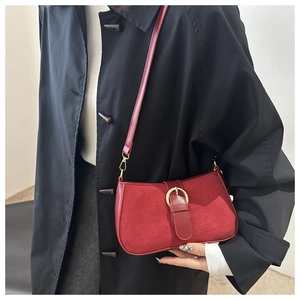 Close-up of red suede and leather underarm bag with gold buckle on a black coat