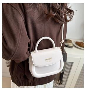 Detail view of cream-white saddle bag with golden FASHION lettering and slim strap