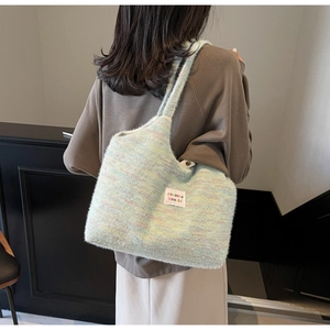 Dettaglio borsa tote in maglia arcobaleno con superficie morbida e toppa con logo