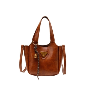 Retro brown leather tote bag with metallic logo and bell charm on a clean white background