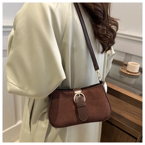 Detail of a vintage dark brown suede shoulder bag with a gold buckle shown on a model