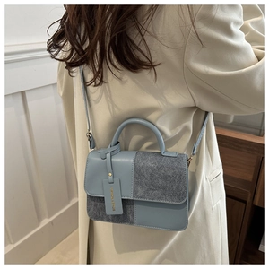 Detailed side view of the blue and grey patchwork crossbody bag worn by a model