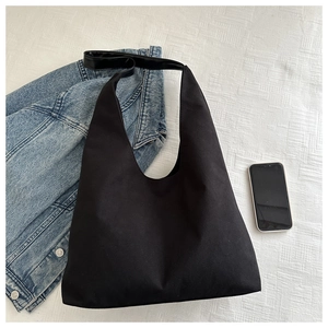 Close-up of black matte canvas hobo bag with wide shoulder strap on fabric texture
