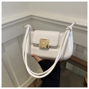 Détail macro du sac baguette blanc avec boucle dorée et bandoulière à nœud artistique