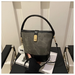 Detail of retro color-block bucket bag featuring grey suede texture and fuzzy monster charm