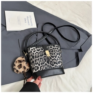 Détail du sac seau léopard avec pendentif cœur sur une veste de costume grise
