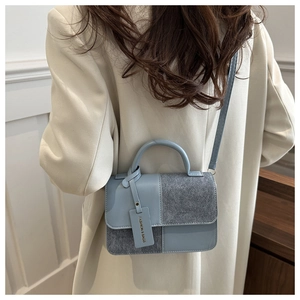 Detail of blue leather and grey felt patchwork handbag shown on a female model