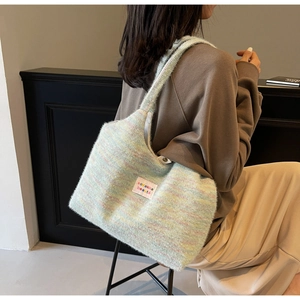Dettaglio della trama di una borsa tote in maglia pastello con etichetta del marchio tessuta