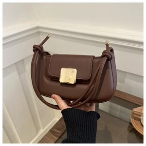 Détail du sac baguette marron foncé avec boucle dorée et bandoulière en corde nouée