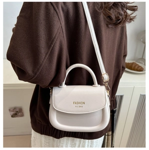 Lifestyle view of cream leather saddle bag with gold hardware and removable strap